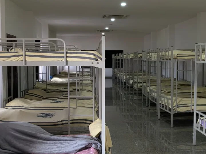 A second view of metal bunk beds and the central aisle in the girls’ hostel at Greenhills