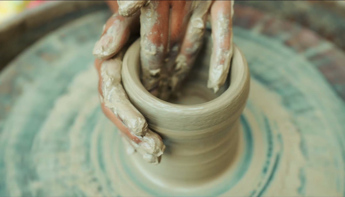 A student shaping clay on a potter’s wheel