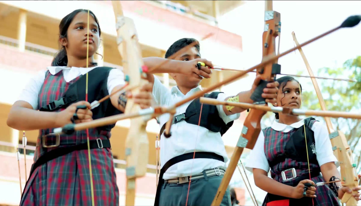 Three Greenhills students drawing their bows at archery practice