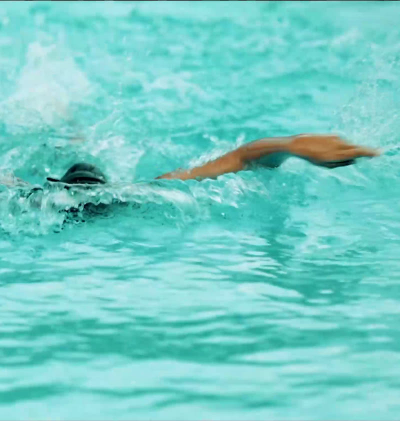 A student swimming freestyle in the school pool